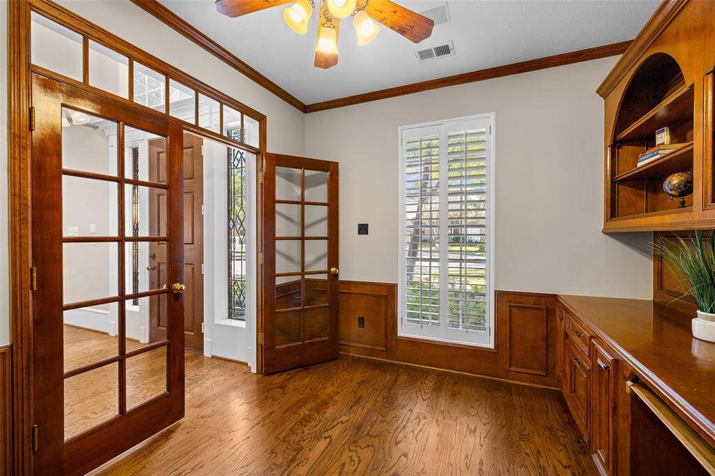 Elegant home office filled with light from large window with plantation shutters, French doors and transom.