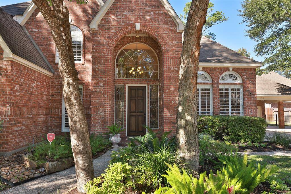 Stunning entrance with arched windows and leaded glass sidelights.  Lush landscaping adds to the beauty of this front entrance.  Welcome home.