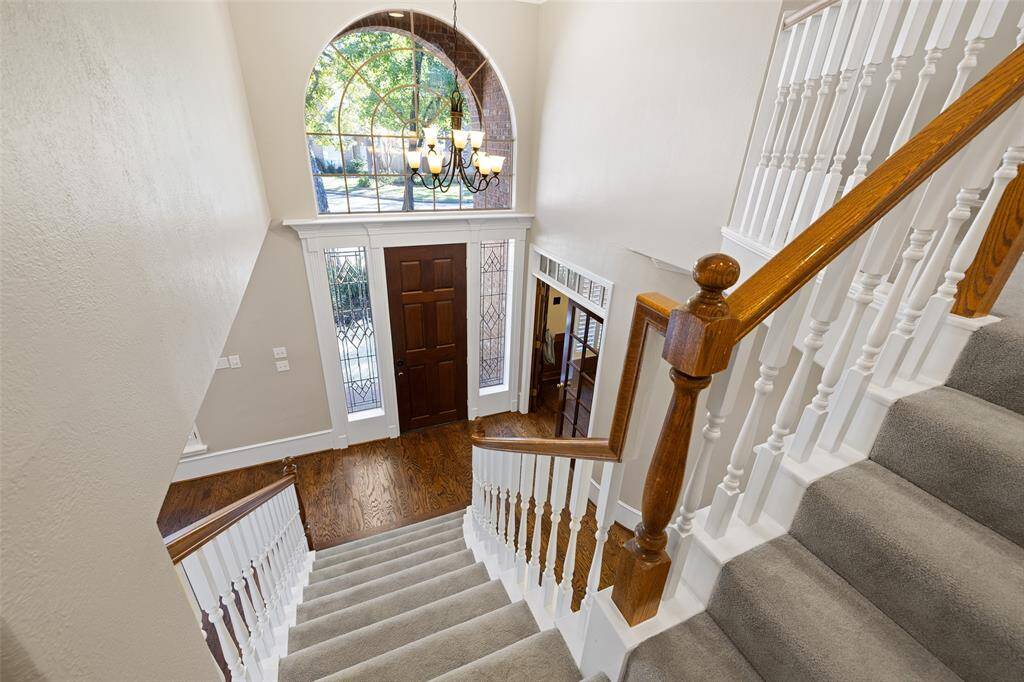 Polished wood flooring complements this elegant foyer which opens to a bright interior - view from upstairs landing of the outdoors through the front large arched window.