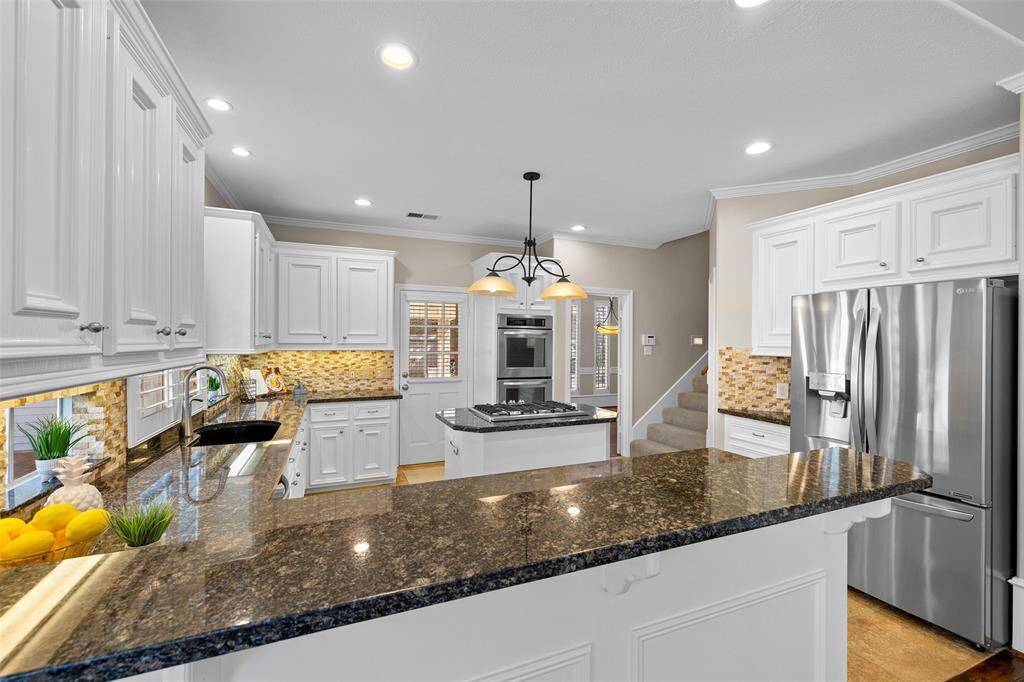 Large kitchen with beautiful granite counters, stone backsplash and undercounter lighting.