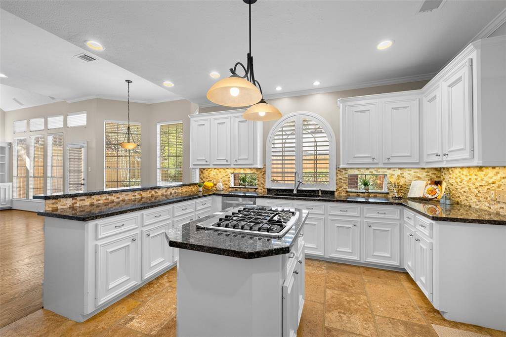 Recessed lighting, attractive light fixture over island and arched and decorative windows provide plenty of light in this lovely kitchen.