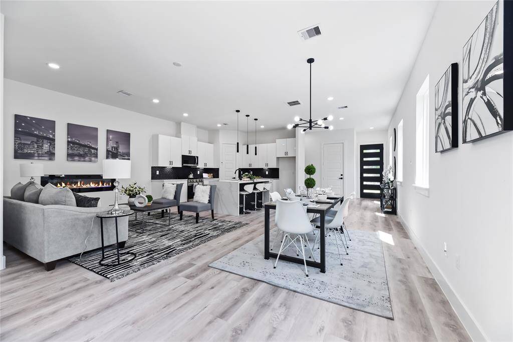 This open-concept living space has that perfect blend of modern style and everyday comfort. You’ve got a cozy fireplace that anchors the room, a sleek kitchen made for cooking (and showing off), and a dining area that’s both stylish and inviting. The large windows let in a ton of natural light, and the clean, contemporary finishes pull everything together. It’s the kind of space that feels just right—whether you’re hosting friends or kicking back for a quiet night in.