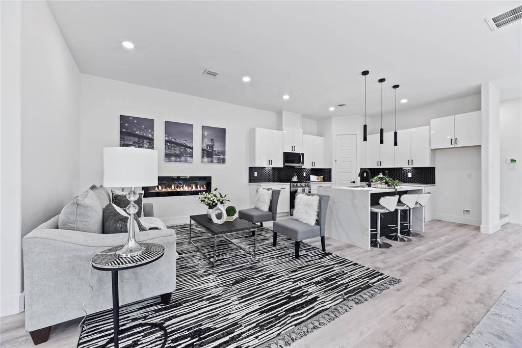 This modern, open-concept space nails the clean, minimalist vibe. The kitchen pops with white cabinetry, a bold black backsplash, and a large island that doubles as bar seating—perfect for casual meals or hanging out while cooking. The whole room feels bright, open, and welcoming… a space that’s as functional as it is stylish.