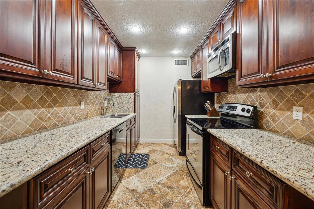 Kitchen features quartz counters, fridge, range, dishwasher, microwave and plenty of storage space