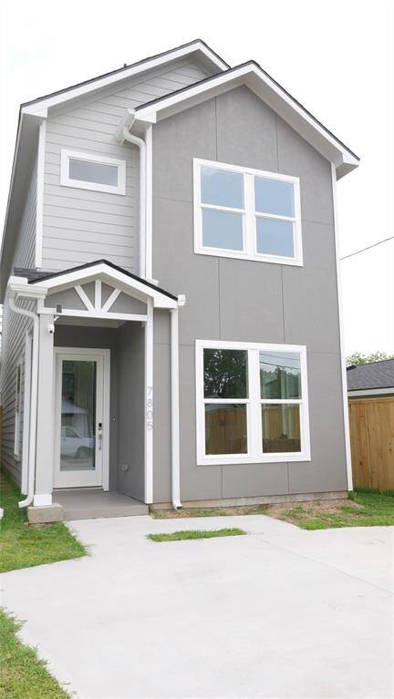 This modern two-story home features a gray exterior with white trim, a front porch, and large windows for natural light. The driveway offers convenient parking, and the fenced yard provides privacy.