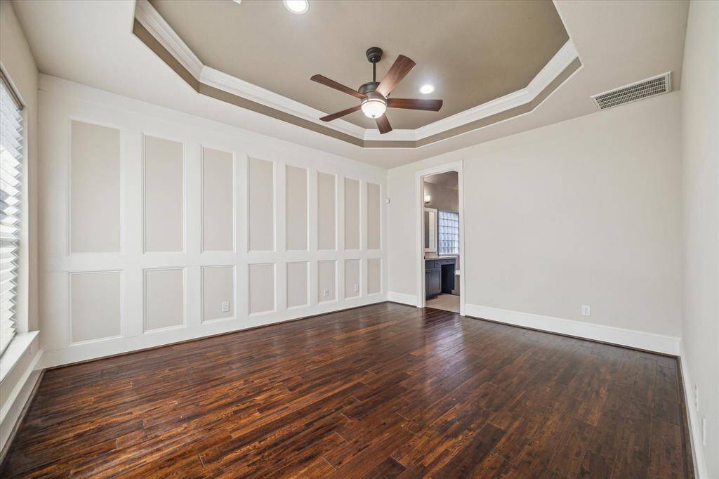 Retreat to the spacious primary bedroom, where double tray ceilings add height and dimension, complemented by picture frame wainscoting for a timeless, custom touch.