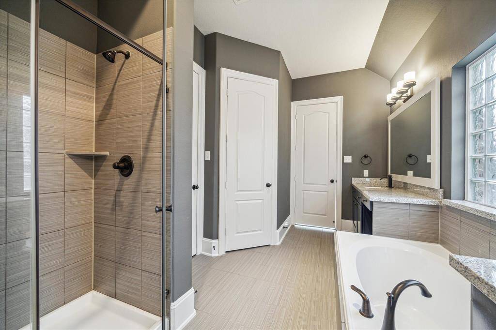 The primary bathroom features dual sinks, a soaking tub for relaxing evenings, and a separate walk-in shower—designed for both comfort and functionality.