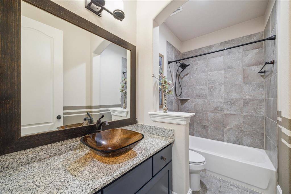 This secondary bathroom features a simple, modern design with granite countertops and a stylish vessel sink—offering both function and flair.