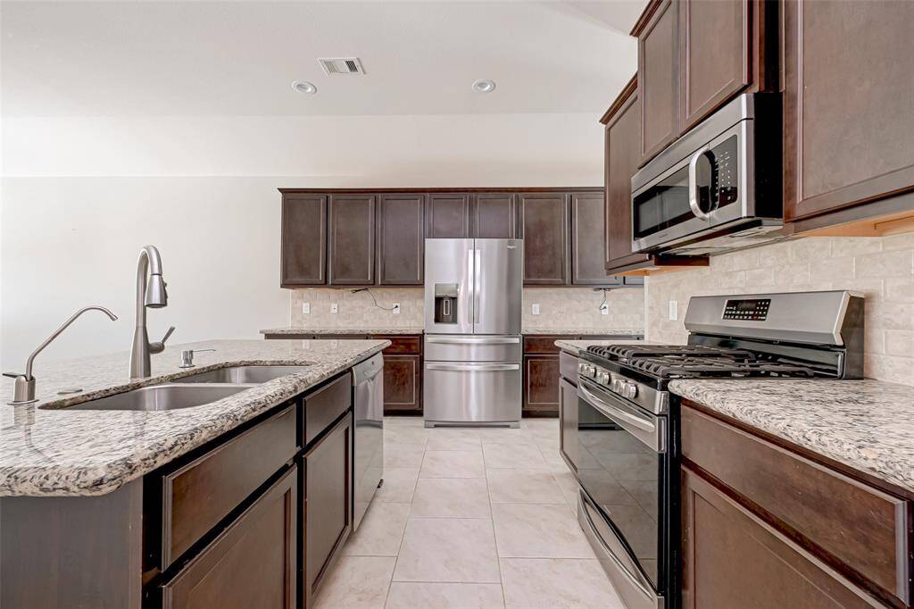 The well-appointed kitchen features modern stainless steel appliances, granite countertops, and ample cabinetry.