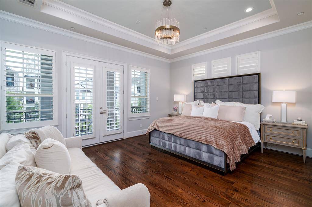 Discover tranquility in this expansive owner's suite, featuring a coffee bar, balcony, and breathtaking waterfront views. Bathed in natural light with elegant wood shutters, this bedroom is truly stunning.
