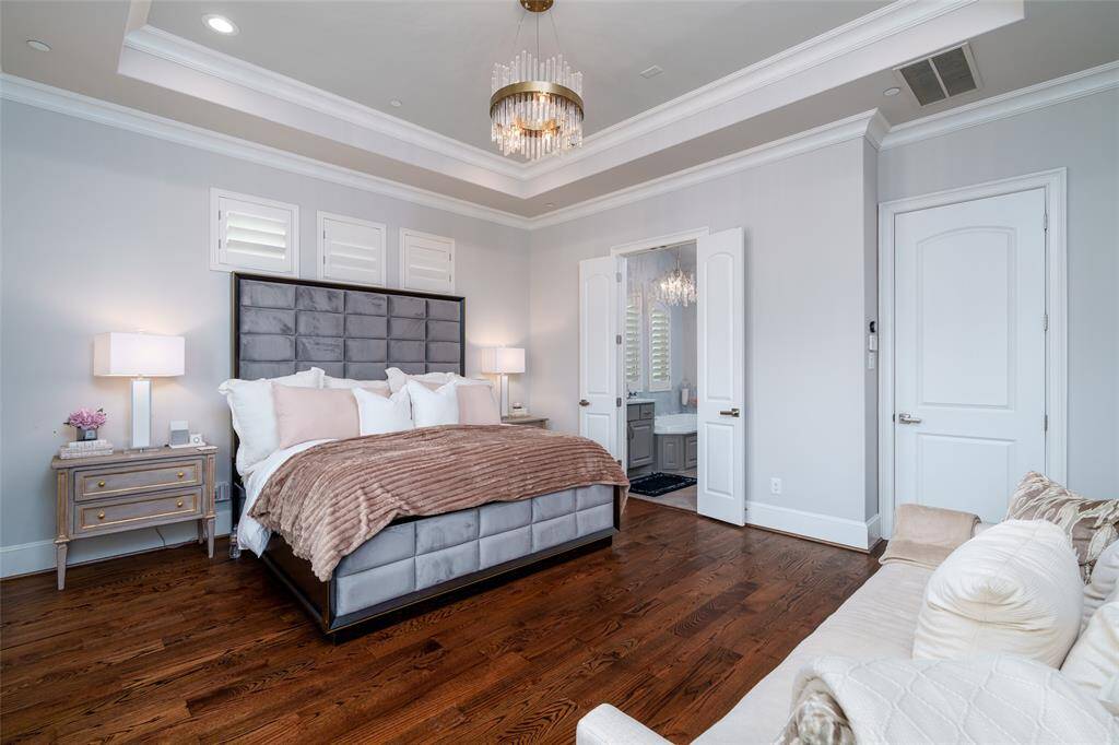 The primary suite features stunning original hardwood floors and elegant double doors opening to a luxurious bathroom.