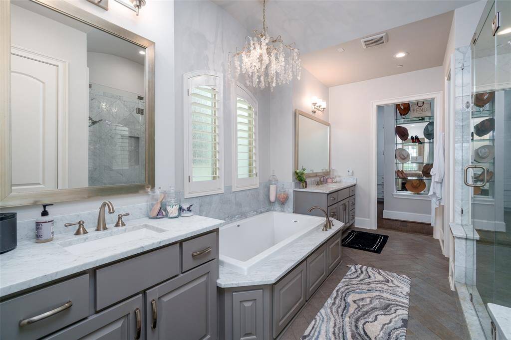 This spa-like primary bathroom boasts an oversized soaking tub, a separate shower, a water closet, and two large vanities, with a beautiful mirrored display leading into the primary closet.