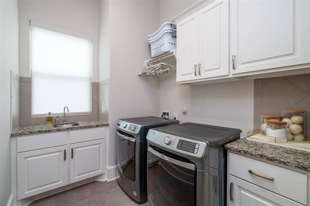 Conveniently located near the primary bedroom, the spacious utility room features a sink, drip-dry area, and ample storage.