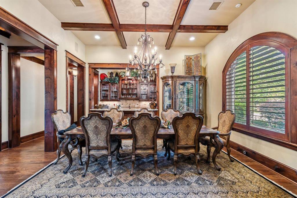 his spacious family room features a cozy stone fireplace, high ceilings with wooden beams, and abundant natural light. The open layout is perfect for relaxation and entertaining. Large windows offer scenic views, enhancing the warm and inviting atmosphere.