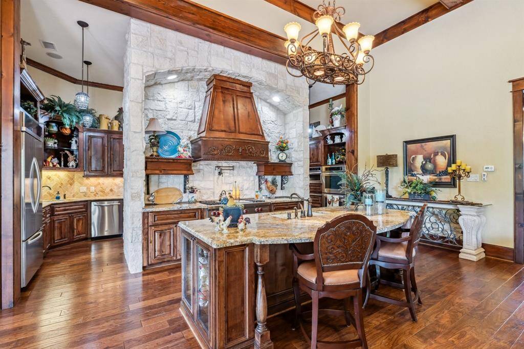 This exquisite butler's pantry features ample cabinetry with pull-out storage, granite countertops, an extra dishwasher for large gatherings, and additional sinks—all set against elegant wood floors.