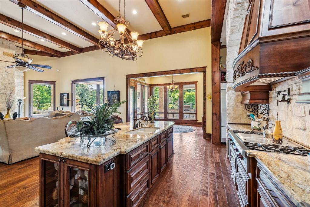 This inviting  breakfast room features large windows with wooden frames that offer a bright, scenic view of the outdoors. It has warm wood flooring and a classic chandelier, creating a cozy and elegant atmosphere.