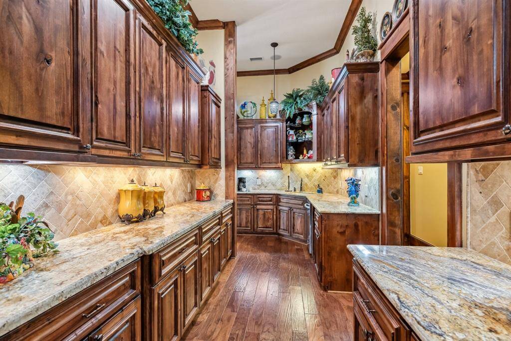 Discover a stunning primary bedroom with elegant tray ceilings, rich wood floors, a stylish ceiling fan, and shutters. Spacious enough for a cozy sitting area.