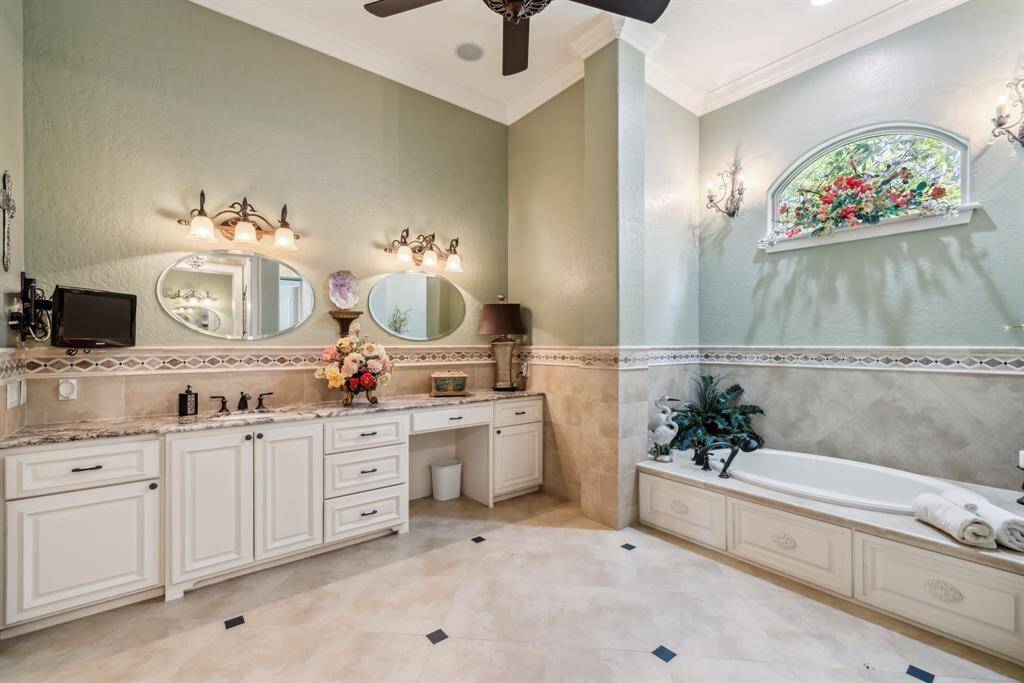 This spacious secondary bedroom features elegant hardwood flooring, a stylish tray ceiling with a ceiling fan, and cam lighting. Ample natural light from the window, creating a warm and inviting atmosphere.