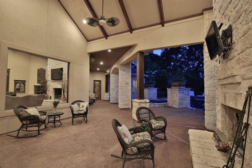 This photo showcases a serene backyard with a luxurious pool and spa featuring a stone waterfall. Surrounded by tall trees, the setting offers a peaceful ambiance, perfect for relaxation or entertaining.