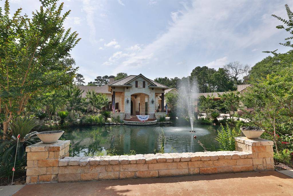 This stunning property features a beautiful stone house with a grand entrance, set amid lush greenery. A charming pond with a central fountain enhances the serene atmosphere, perfect for relaxation and outdoor enjoyment.