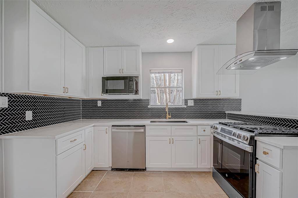 You'll love cooking in your freshly remodeled kitchen complete with white shaker cabinets, black herringbone backsplash, stainless steel appliances, quartz countertops and gold accents.