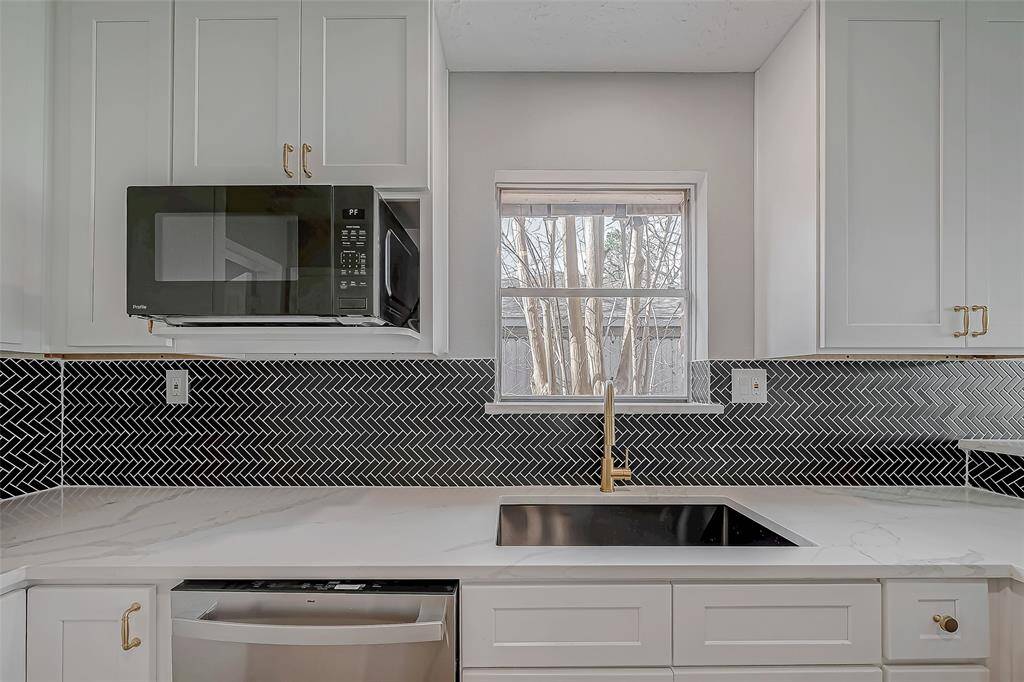You'll feel like you've stepped into an interior design magazine: black herringbone backsplash, gorgeous quartz countertops, modern gold hardware and a deep single-basin sink.