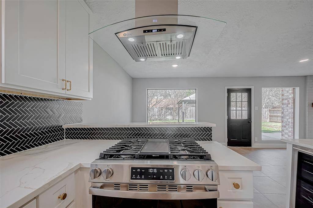 This gourmet kitchen includes a stainless gas range with built-in griddle and it's topped with a beautiful, contemporary stainless and glass hood vent.