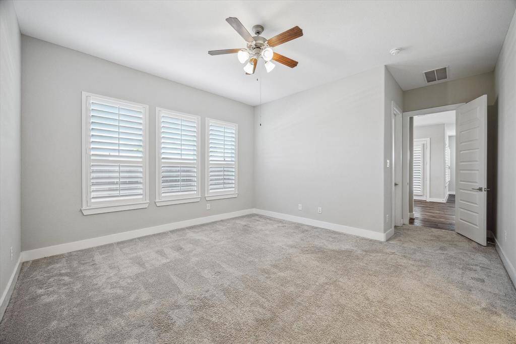 Primary Bedroom with plantation shutters and plush neutral carpet.