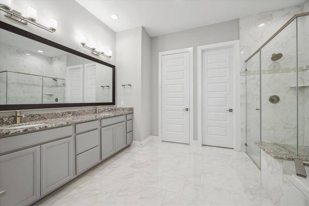 Primary Bathroom with large double vanity with frames mirror, soaking tub, walk-in shower, tile floors.