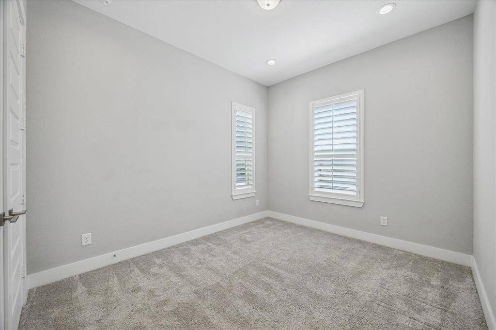 One of two secondary bedrooms with plush carpet and plantation shutters.