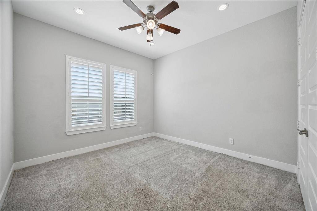 The second of two secondary bedrooms with plush carpet and plantaion shutters.