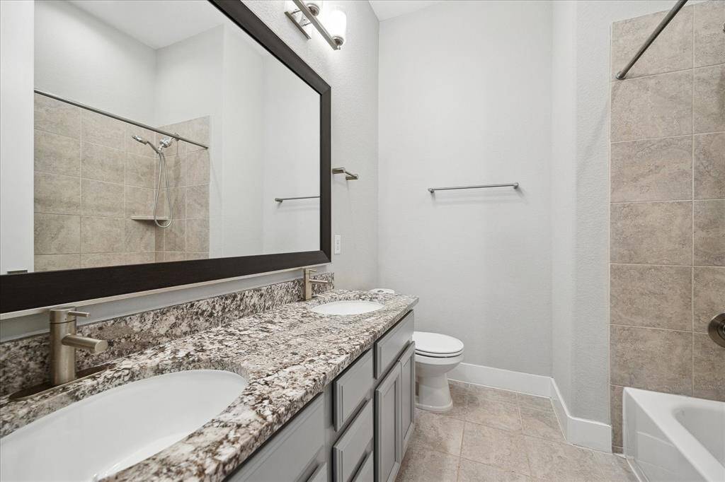Second Full Bath with double vanity and large frames mirror, combination tub/shower, tile floors.