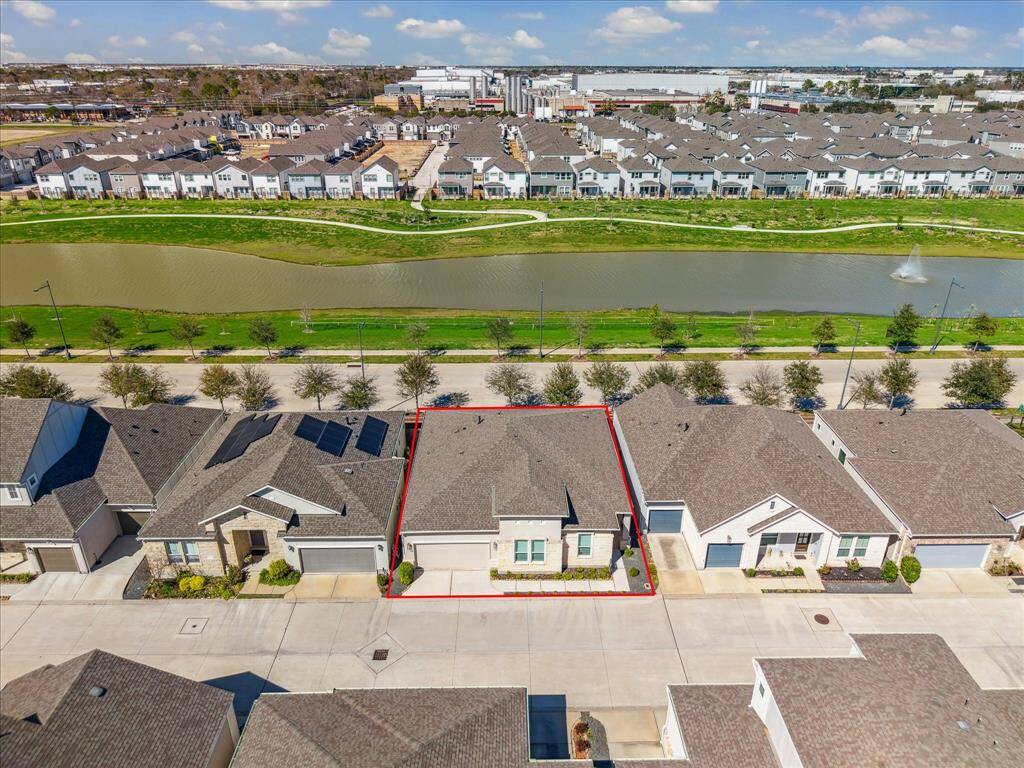 View of home from overhead showing perimeter of lot and community lake.