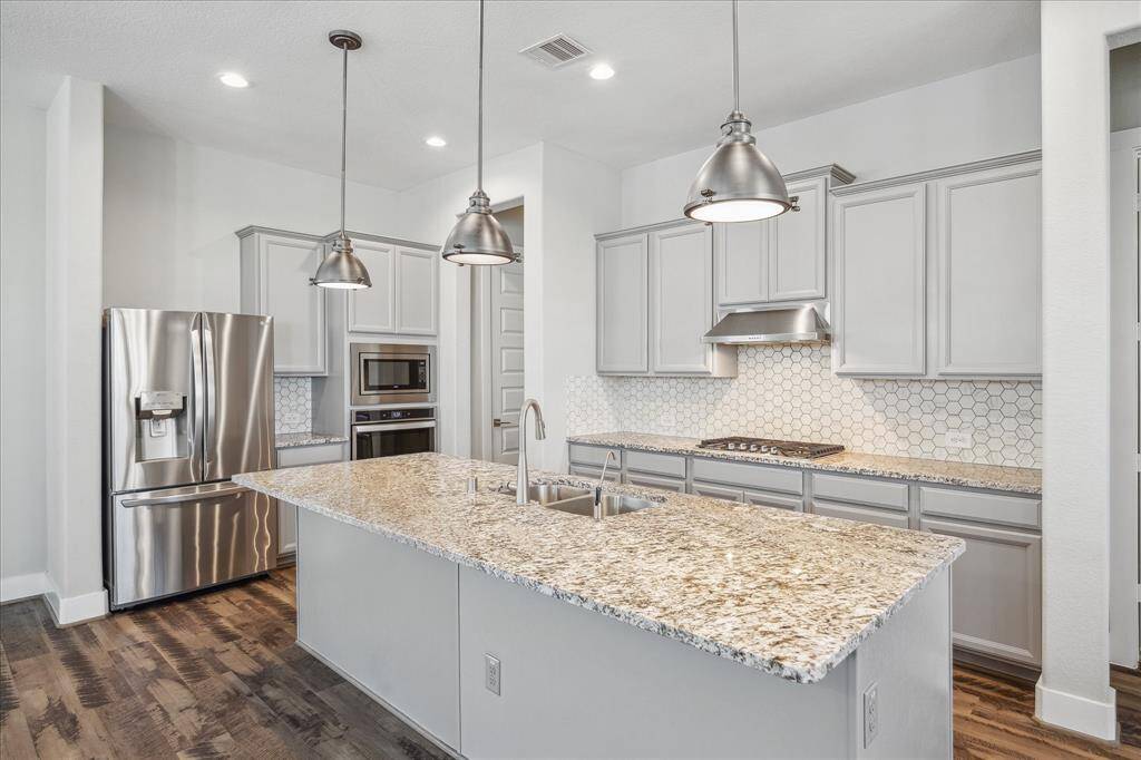 Open Kitchen with quartz counter tops, stainless steel appliances and side by side refrigerator/freezer.