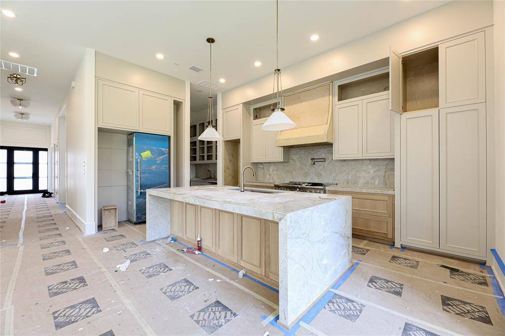 A gorgeous extra large Taj Mahal quartzite island w/ waterfall edge is the centerpiece of this Chef's Kitchen. Breakfast nook to the right w/ many windows and transoms.