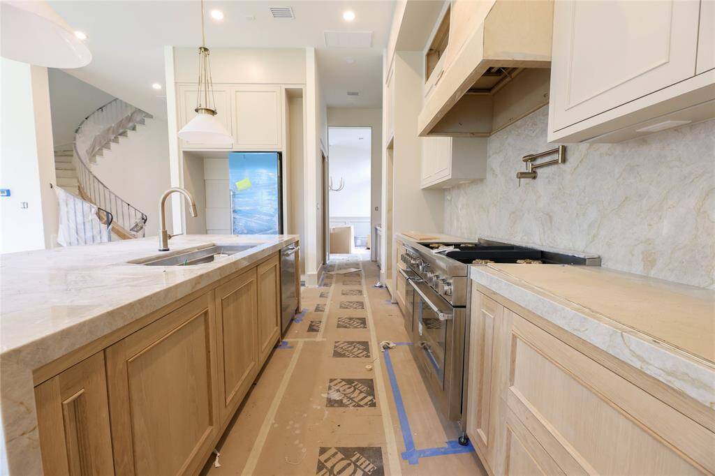 Chef's Kitchen offers Taj Majal Quartz counters w/ waterfall edge, Custom site-built cabinetry, Kitchenaid 48" gas range w/ double oven & pot-filler. Kitchen leads to Butler's Pantry, walk-in pantry & formal dining room.
