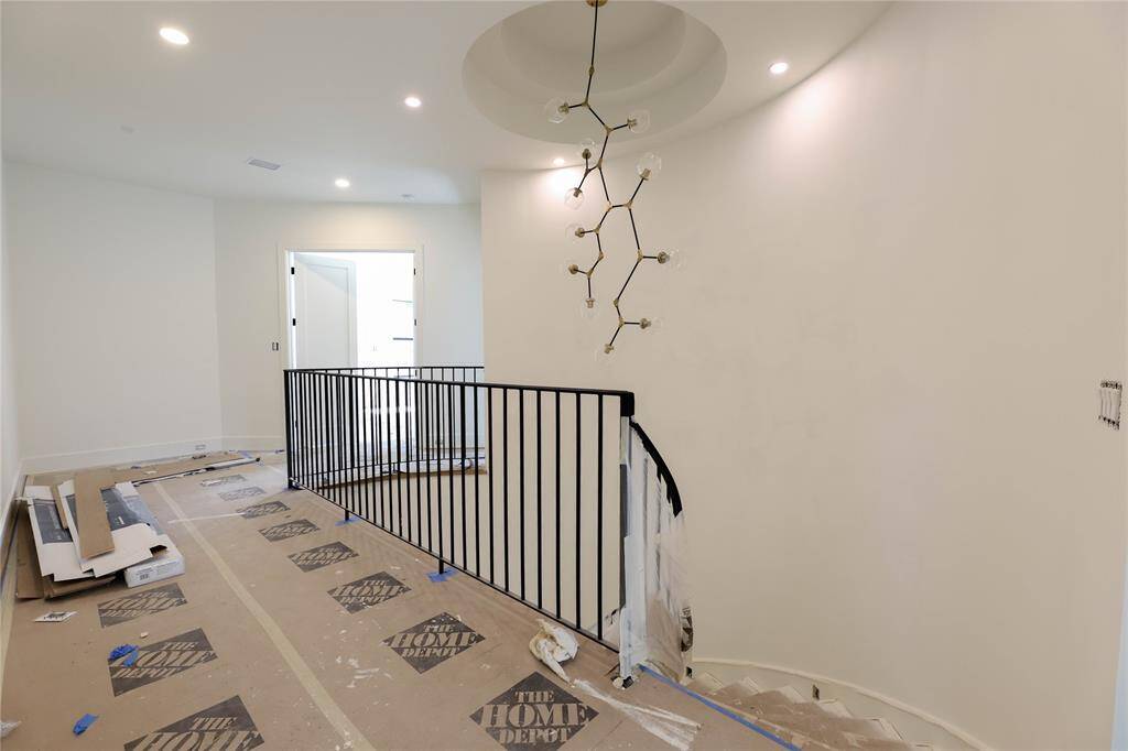 Up the spiral staircase leads to wide hallway w/ the primary suite on one side of the home and secondary bedrooms/Game Room on the opposite side. Rotunda ceiling detail & contemporary chandelier.