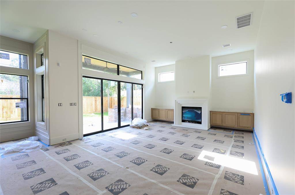 Family Room is spacious w/ living room built-ins, gas Fireplace & wall of sliding windows leading out to the covered patio & Summer Kitchen. Transoms let in an abundant amount of natural light.
