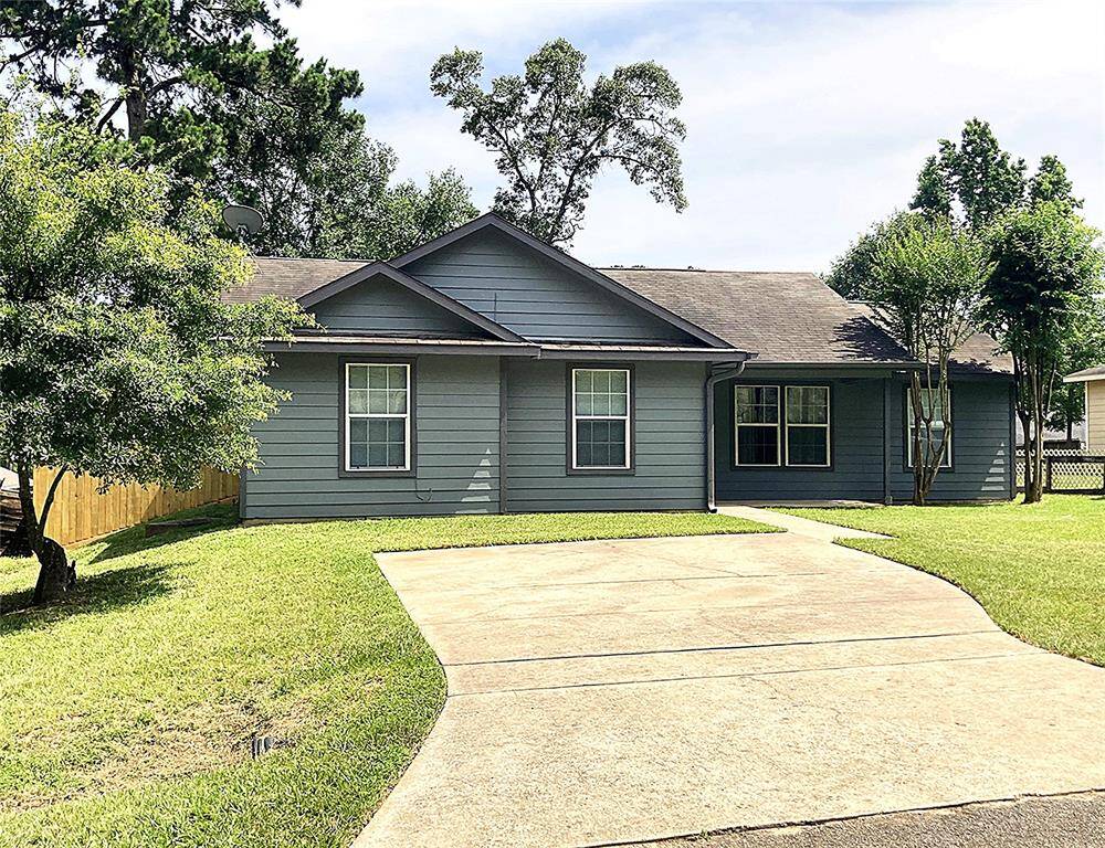 This is a charming single-story home with a modern gray exterior. It is surrounded by a lush lawn and mature trees. The setting is serene and inviting, ideal for a comfortable lifestyle.