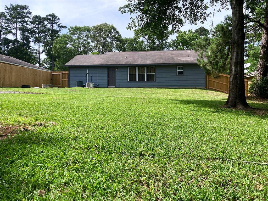 Spacious, well-maintained backyard. Surrounded by a wooden fence, offering privacy. Tall trees provide a natural backdrop, adding to the serene setting.