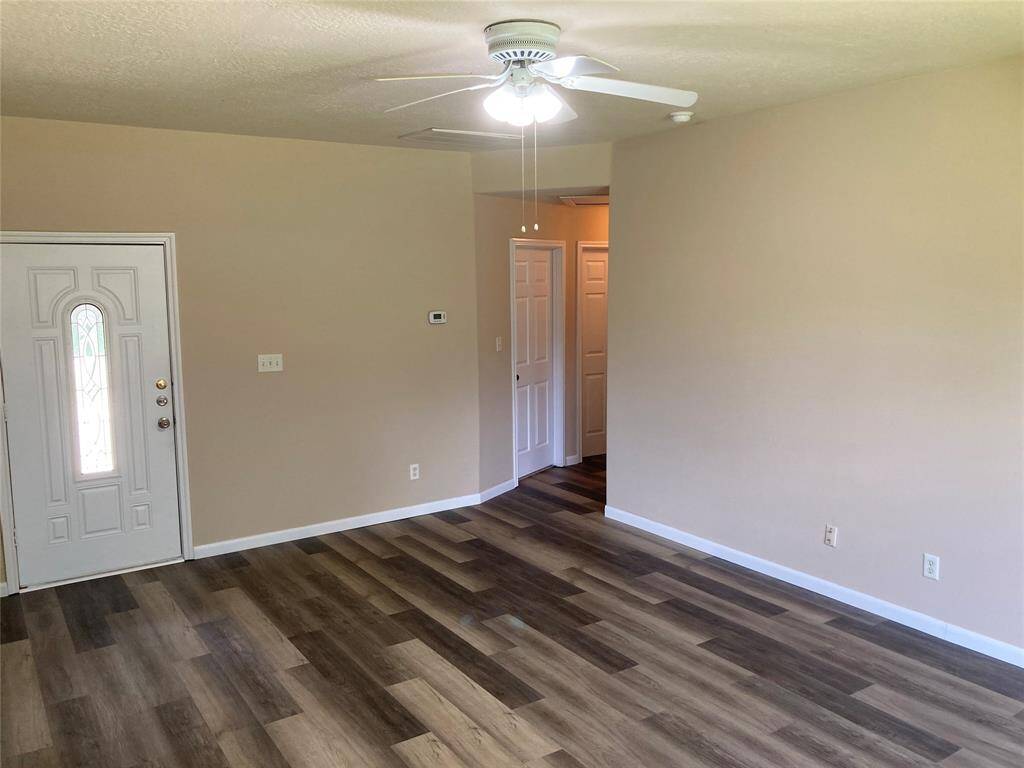 The space is bright and open, ideal for versatile living This room features neutral walls and wood-look flooring, creating a warm and inviting atmosphere.