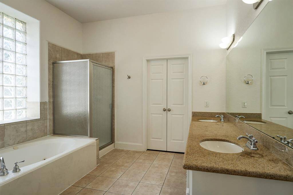 Downstairs master Bathroom with oval tub , separate shower, linen closet, large vanity double sinks, and walk-in closet