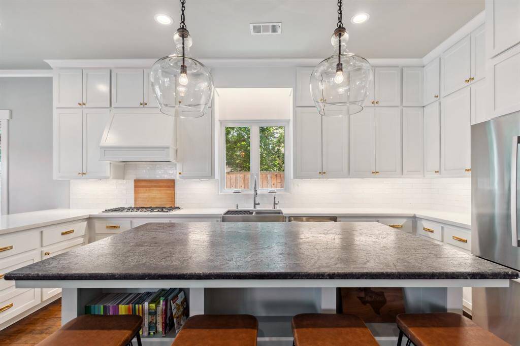 The center island/breakfast bar welcomes casual meals under gorgeous glass pendants.