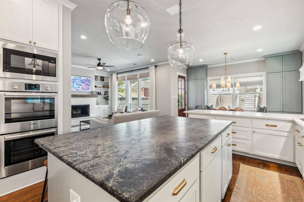 The stainless steel appliances include a vented gas range, wall ovens, a side-by-side refrigerator, a built-in microwave and a dishwasher.
