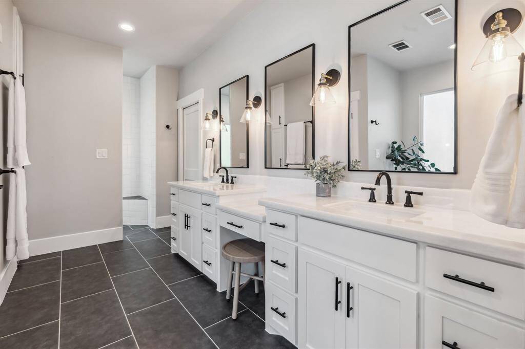The remodeled primary bathroom impresses with two large marble vanities flanking a knee space. Large-format floor tile runs throughout, while a private water closet adds convenience.