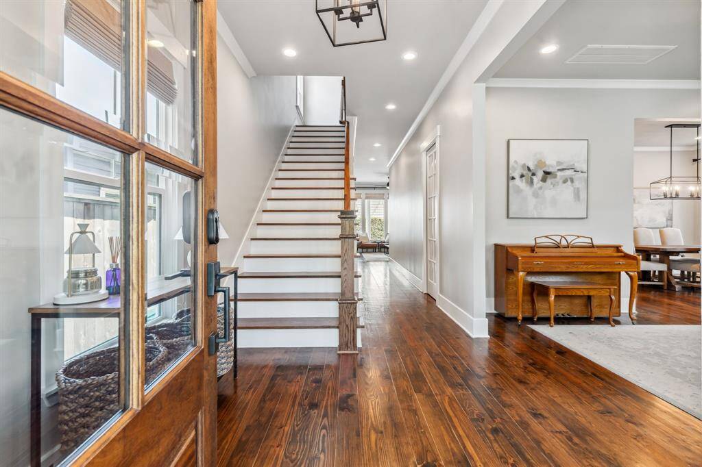 A beautiful wood door with sidelights welcomes you inside the 3,030-square-foot home where tall ceilings trimmed with recessed lighting, designer fixtures and crown molding soar above refinished hardwood floors.