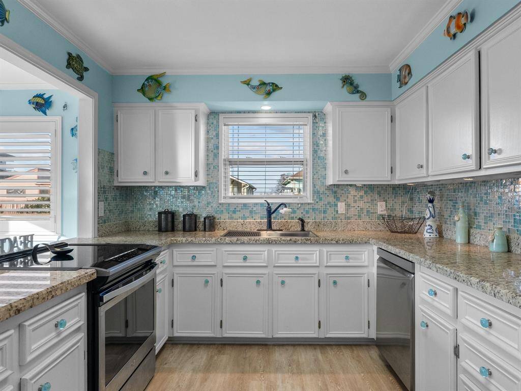 The glass backsplash matches the glass knobs in this seaside kitchen.