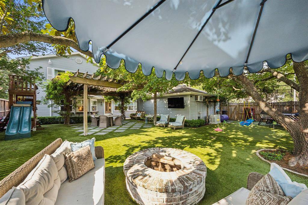 Amazing turfed backyard with fire pit, putting green, and pergola with pavers.