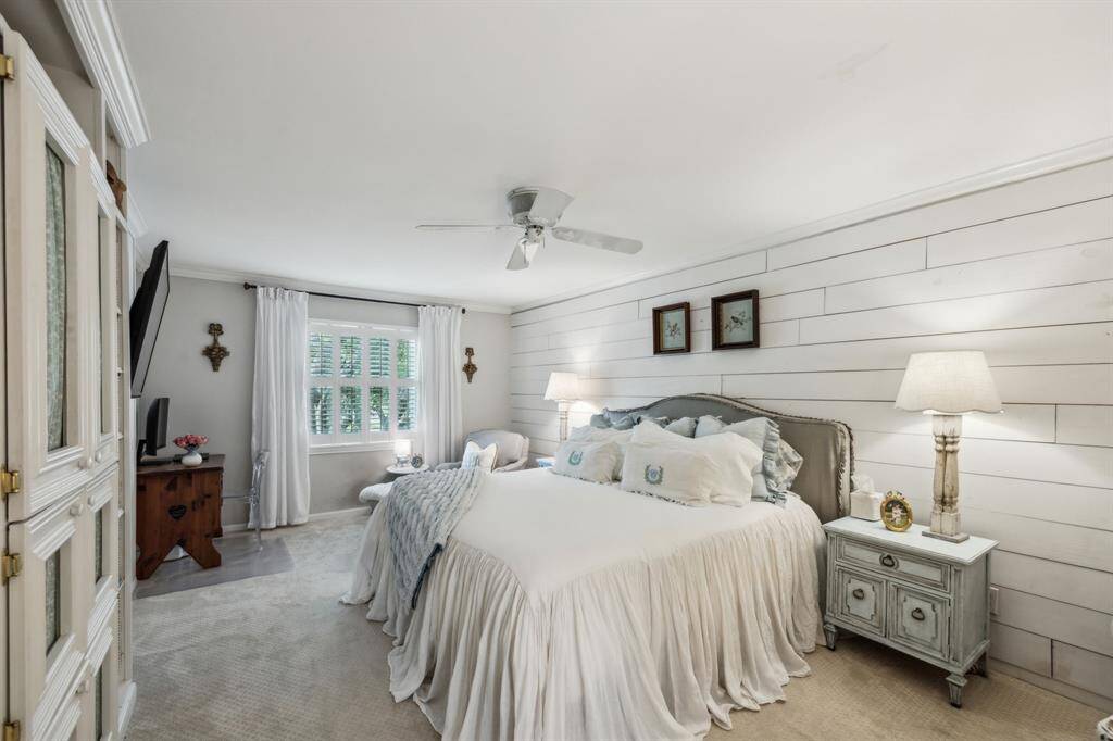 Primary suite features ceiling fan, shiplap wall accents, plantation shutters, and incredible lavish bath.