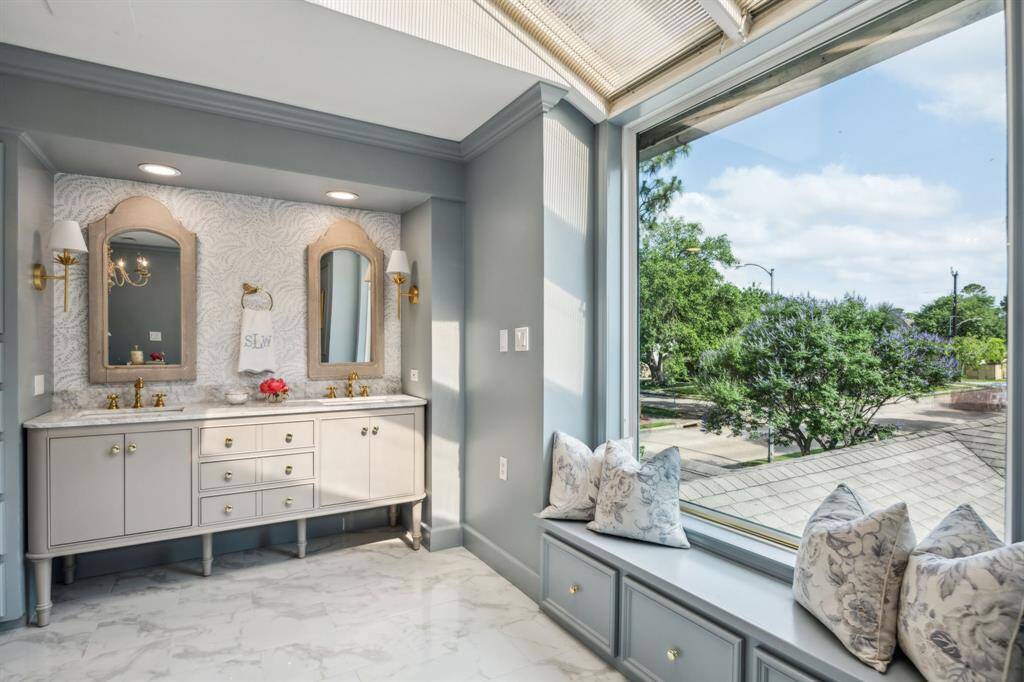 Absolutely exquisite primary bath with custom vanity, separate shower, freestanding soaking tub, window, and skylights.